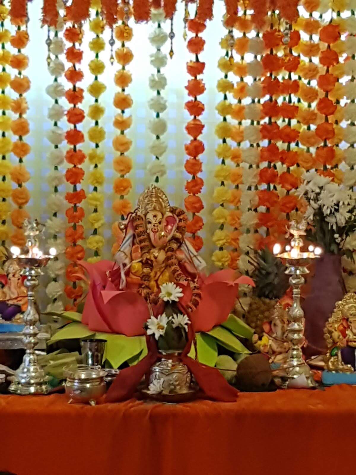 Close-up of Lord Ganesha decorated with flowers and silver lamps, 2017