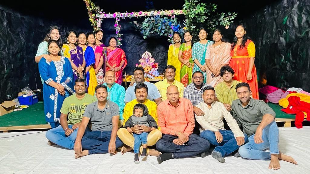 Large community group photo in front of the grand floral Ganesh mandap, 2024